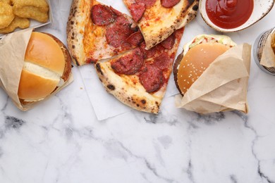 Photo of Different delicious fast food on white marble table, flat lay. Space for text