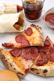 Photo of Different delicious fast food and soda drink on white marble table, closeup