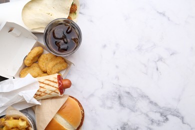Photo of Different delicious fast food and soda drink on white marble table, flat lay. Space for text