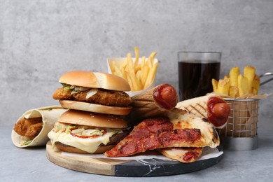 Photo of Different delicious fast food and soda drink on grey table, closeup