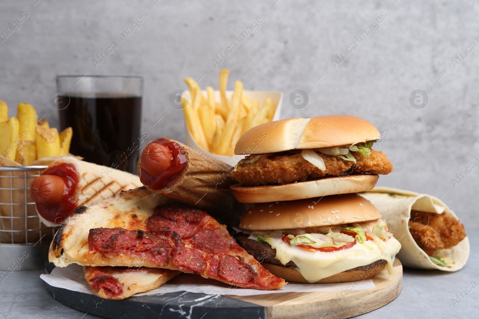 Different delicious fast food and soda drink on grey table, closeup Photo of Different delicious fast food and soda drink on grey table, closeup