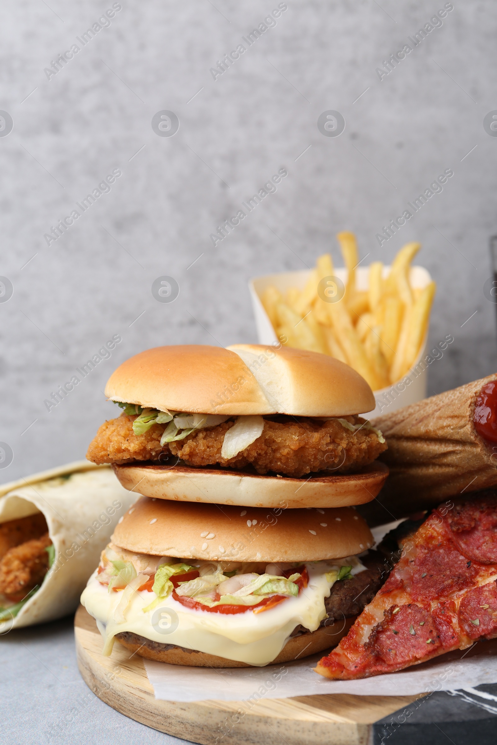 Different delicious fast food on grey table, closeup Photo of Different delicious fast food on grey table, closeup