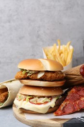 Photo of Different delicious fast food on grey table, closeup
