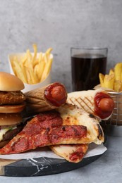 Photo of Different delicious fast food and soda drink on grey table, closeup