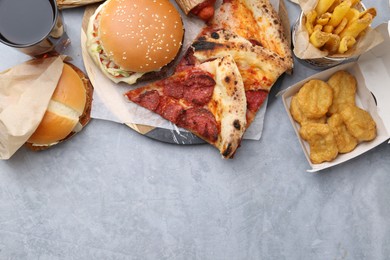 Photo of Different delicious fast food and soda drink on grey table, flat lay. Space for text