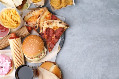 Photo of Different delicious fast food and soda drink on grey table, flat lay. Space for text