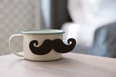 Photo of Happy Father's Day. Cup with mustache on wooden table at home, closeup. Space for text