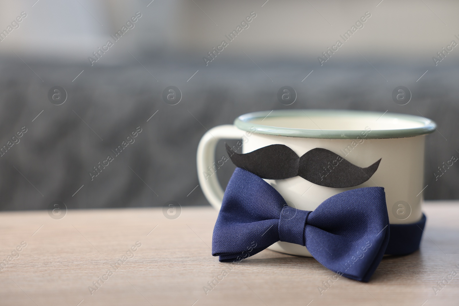 Happy Father's Day. Cup with mustache and bowtie on wooden table at home, closeup. Space for text Photo of Happy Father's Day. Cup with mustache and bowtie on wooden table at home, closeup. Space for text
