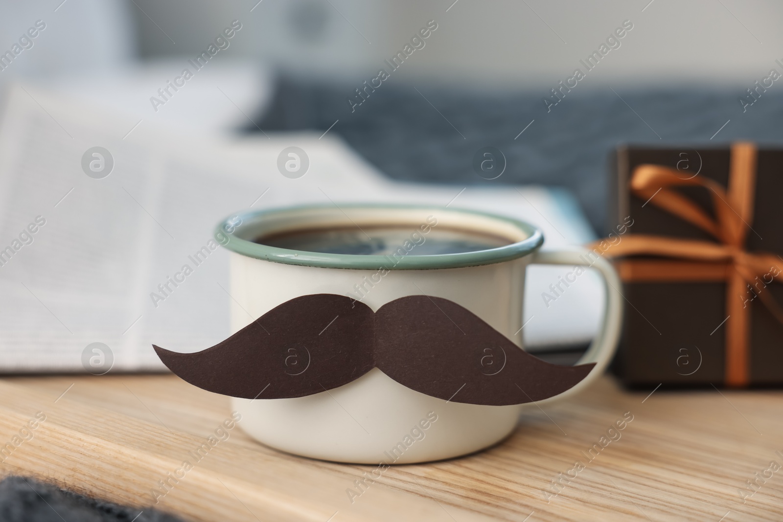 Happy Father's Day. Cup with mustache and gift on bed at home, closeup Photo of Happy Father's Day. Cup with mustache and gift on bed at home, closeup