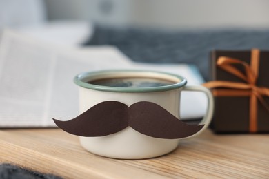 Photo of Happy Father's Day. Cup with mustache and gift on bed at home, closeup