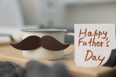 Photo of Happy Father's Day card and cup with mustache on bed at home, closeup