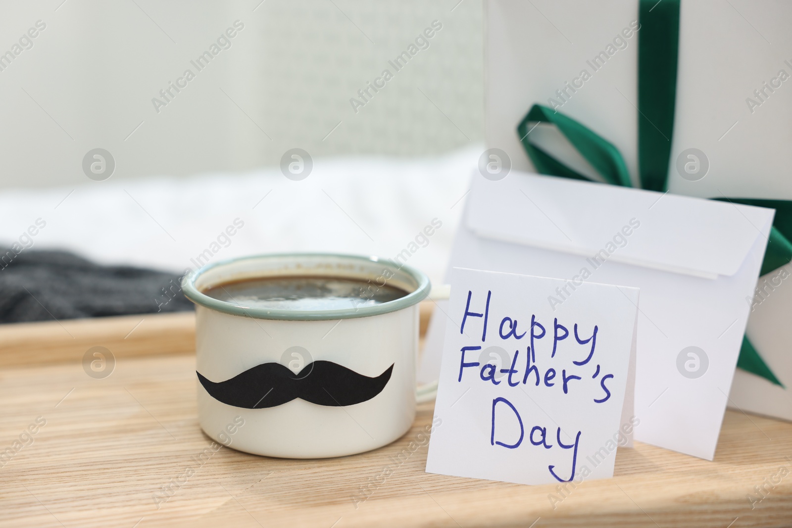 Happy Father's Day card, cup with mustache, gift and envelope on bed at home, closeup Photo of Happy Father's Day card, cup with mustache, gift and envelope on bed at home, closeup