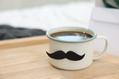 Photo of Happy Father's Day. Cup with mustache on bed at home, closeup. Space for text