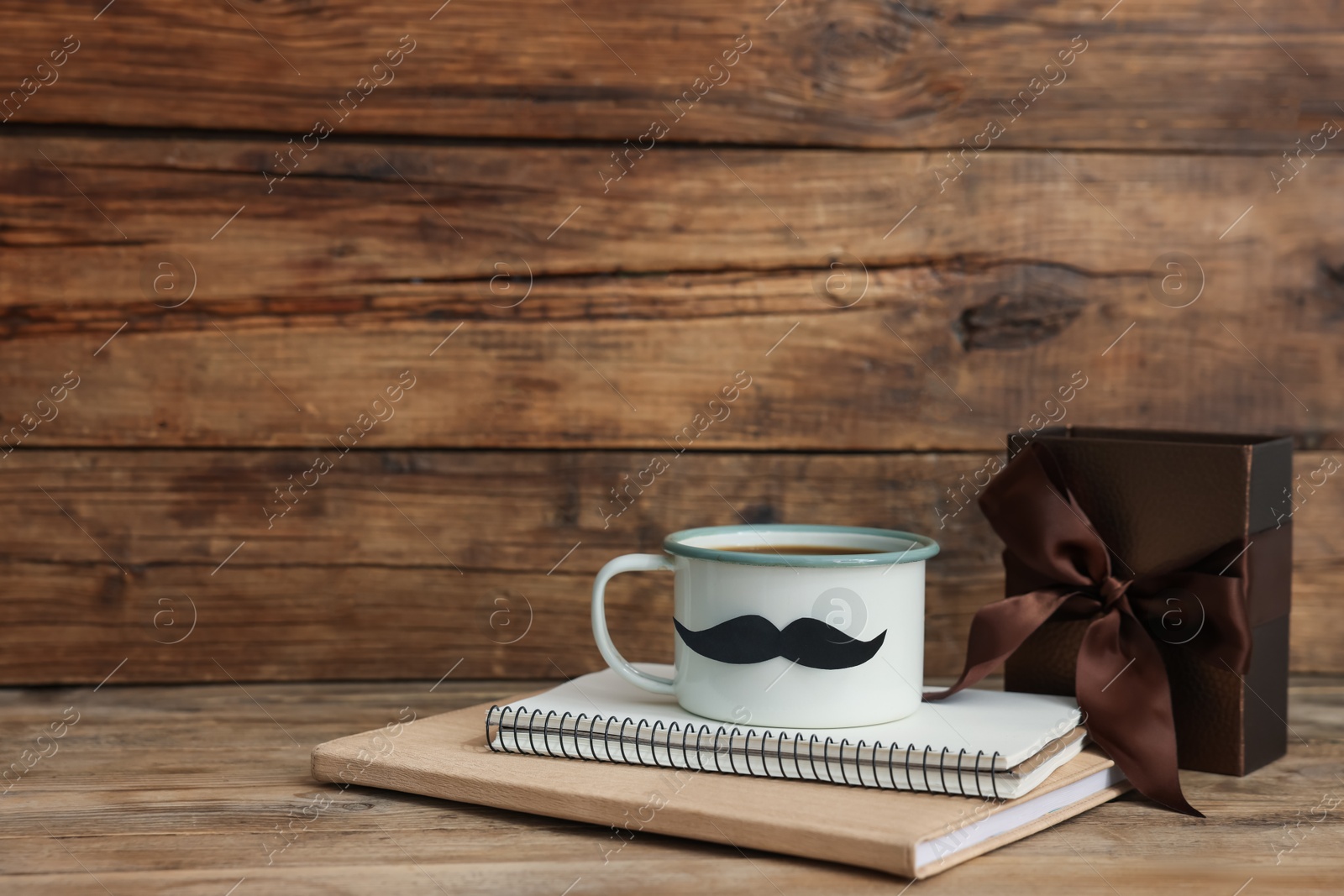 Happy Father's Day. Cup with mustache, notebooks and gift on wooden table. Space for text Photo of Happy Father's Day. Cup with mustache, notebooks and gift on wooden table. Space for text