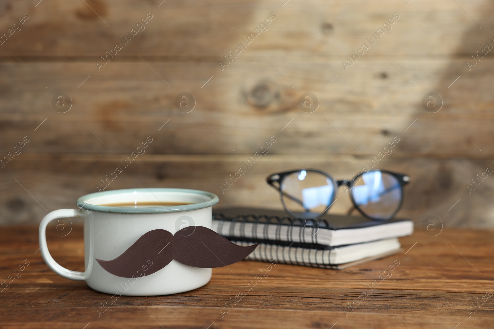 Happy Father's Day. Cup with mustache, notebooks and glasses on wooden table. Space for text Photo of Happy Father's Day. Cup with mustache, notebooks and glasses on wooden table. Space for text