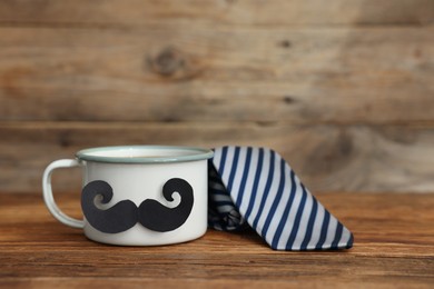 Photo of Happy Father's Day. Cup with mustache and tie on wooden table. Space for text