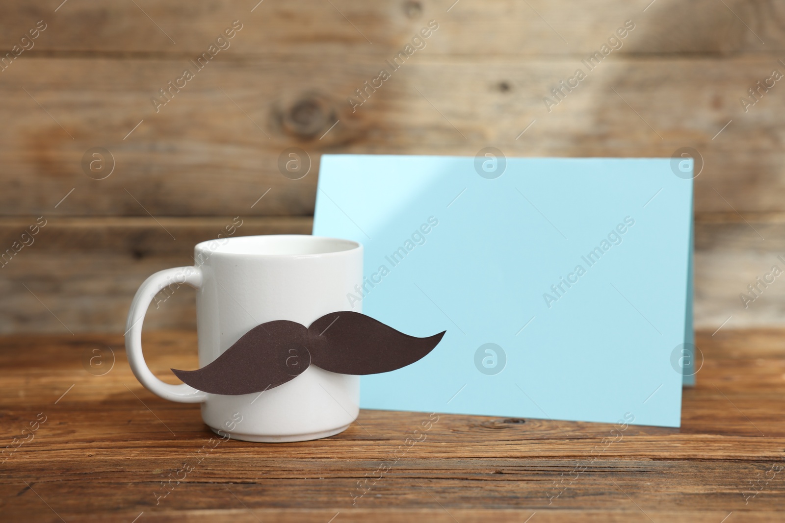 Happy Father's Day. Cup with mustache and card on wooden table. Space for text Photo of Happy Father's Day. Cup with mustache and card on wooden table. Space for text
