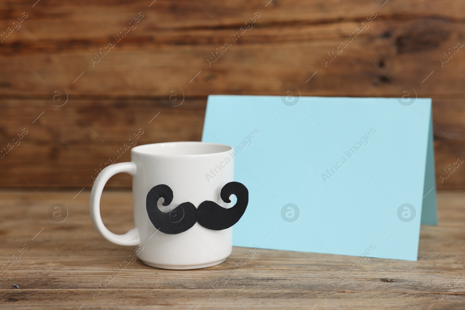 Happy Father's Day. Cup with mustache and card on wooden table. Space for text Photo of Happy Father's Day. Cup with mustache and card on wooden table. Space for text