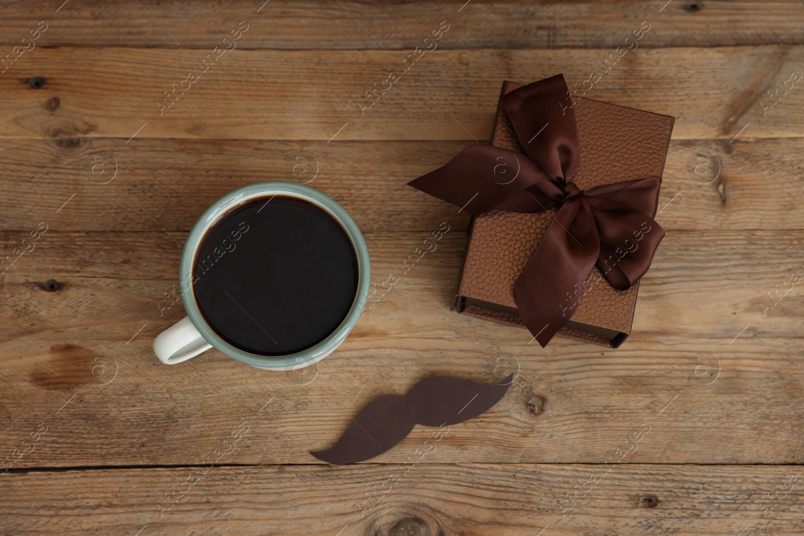 Happy Father's Day. Cup with mustache and gift on wooden table, flat lay Photo of Happy Father's Day. Cup with mustache and gift on wooden table, flat lay