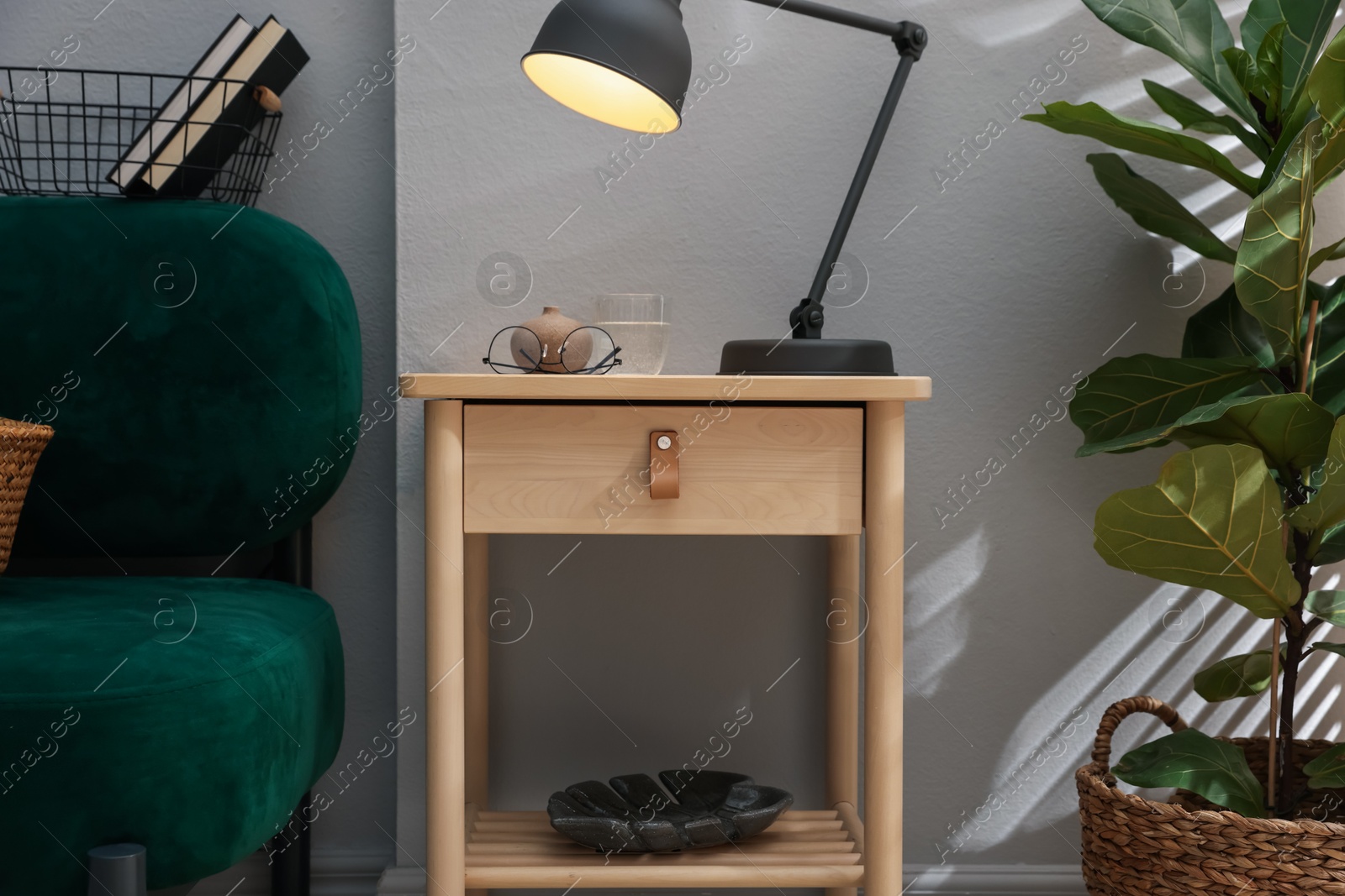 Wooden side table with glass of water, lamp and glasses indoors Photo of Wooden side table with glass of water, lamp and glasses indoors