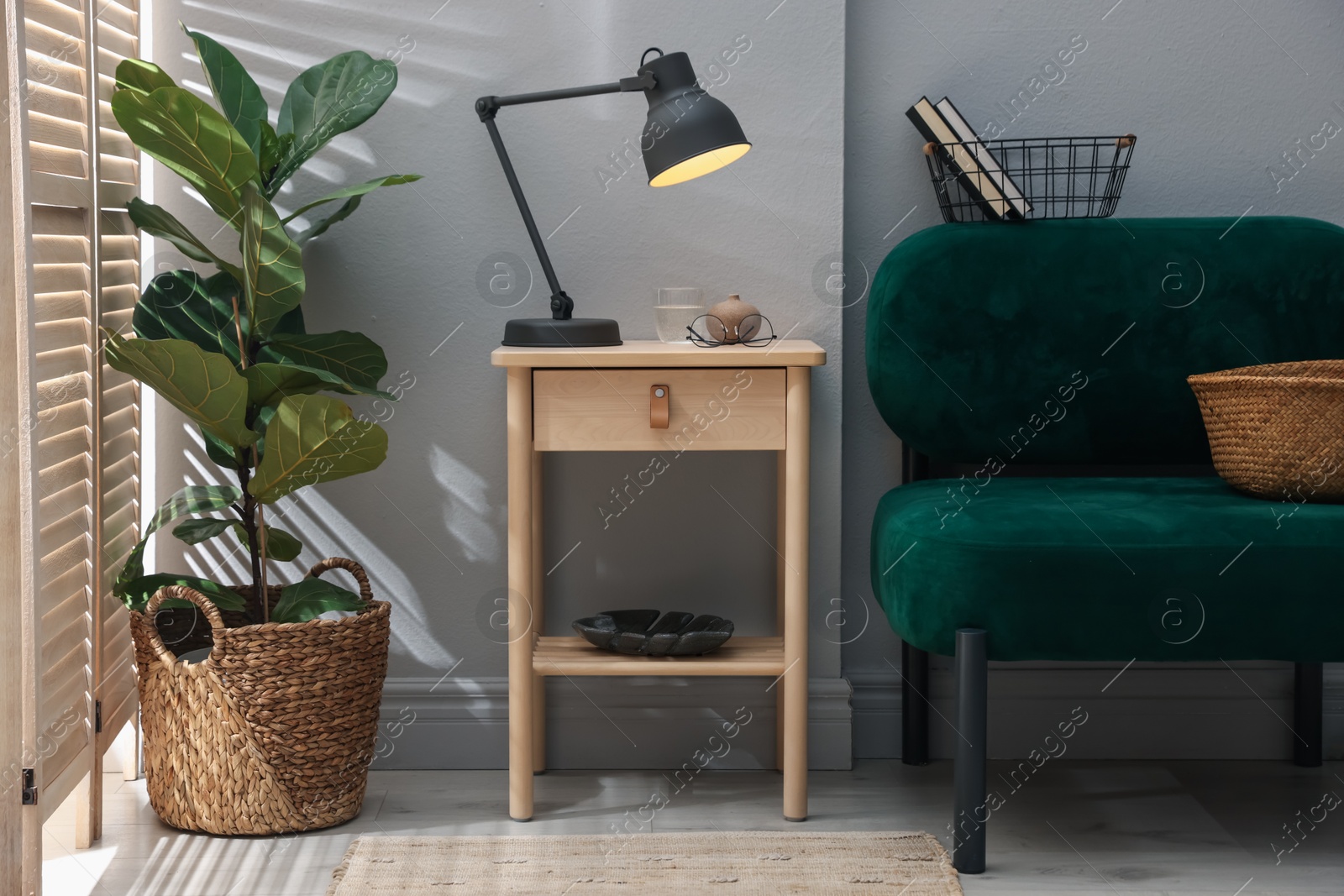 Wooden side table with glass of water, lamp and glasses indoors Photo of Wooden side table with glass of water, lamp and glasses indoors
