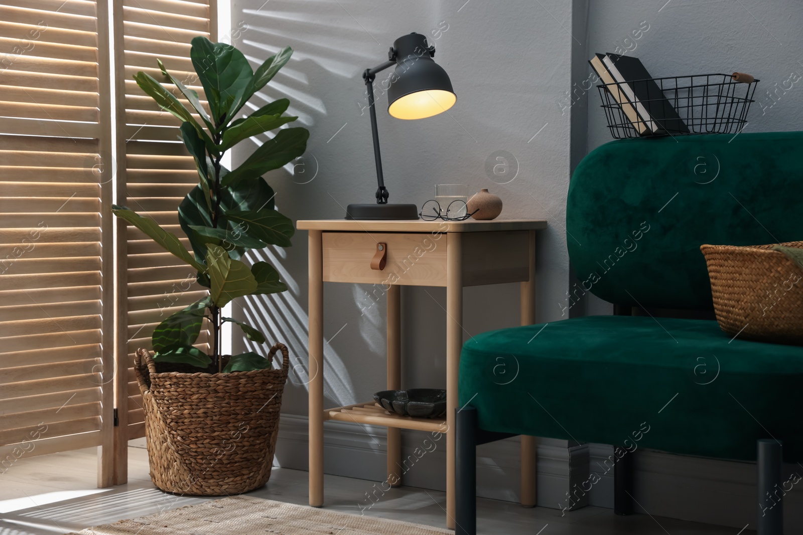 Wooden side table with glass of water, lamp and glasses indoors Photo of Wooden side table with glass of water, lamp and glasses indoors