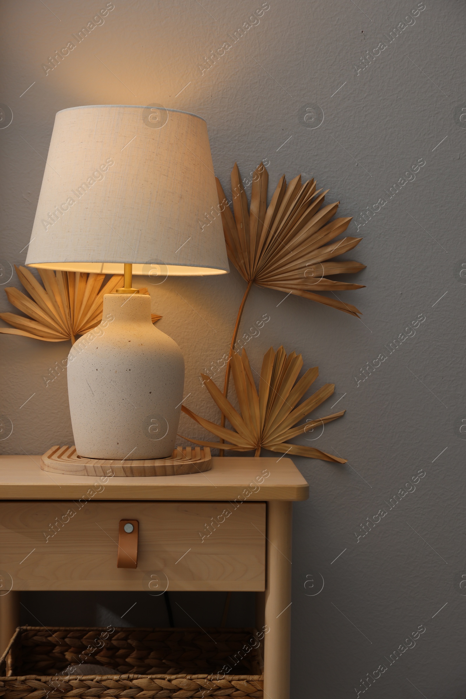 Stylish wooden side table with lamp near light wall at home Photo of Stylish wooden side table with lamp near light wall at home