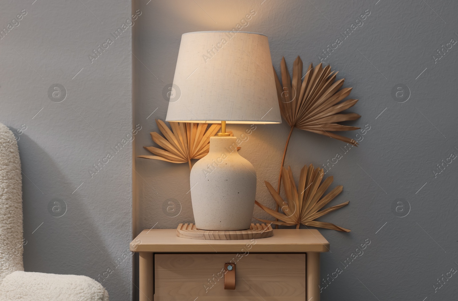 Stylish wooden side table with lamp near light wall at home Photo of Stylish wooden side table with lamp near light wall at home