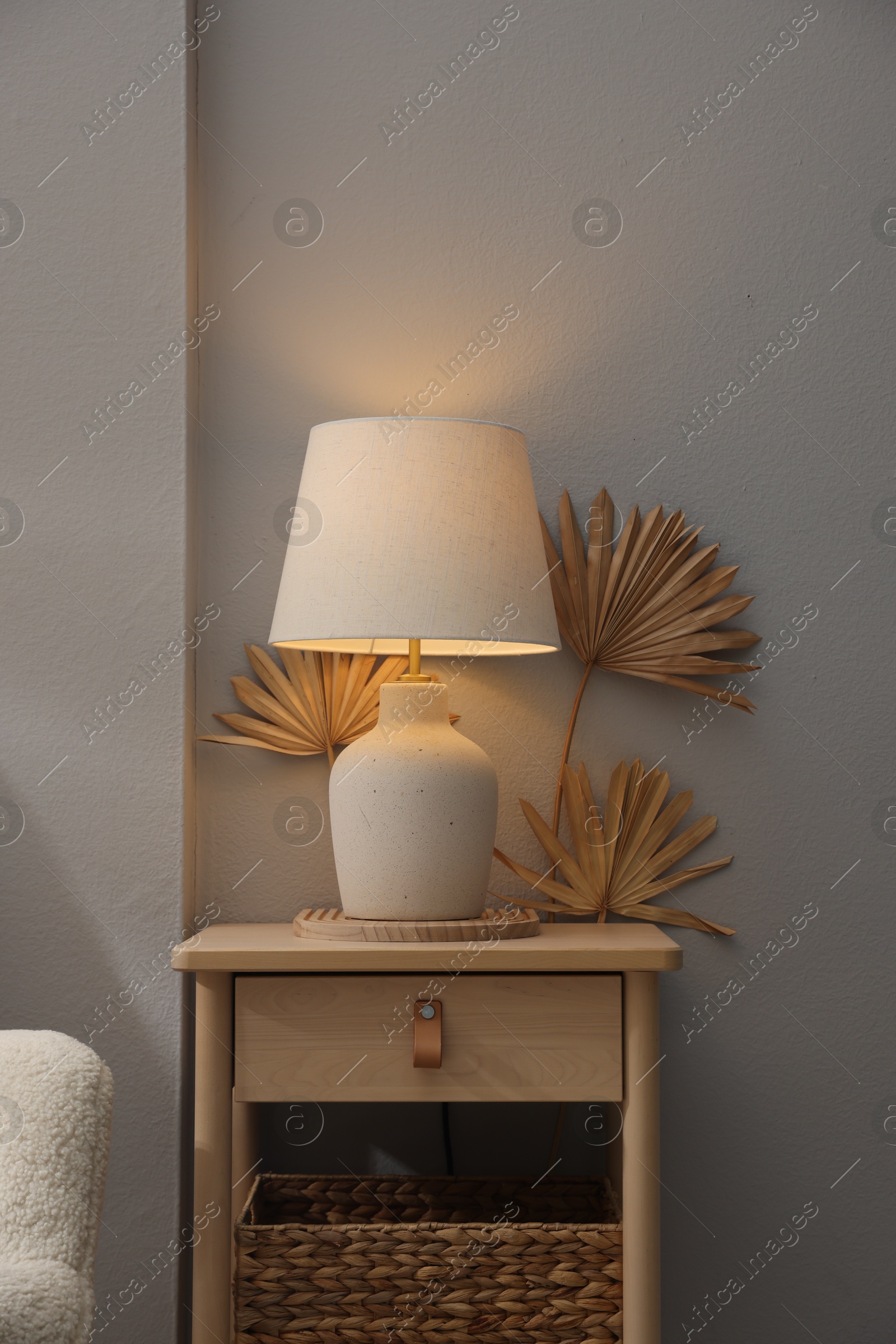 Stylish wooden side table with lamp near light wall at home Photo of Stylish wooden side table with lamp near light wall at home