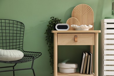 Photo of Wooden side table with stylish decor near green wall indoors