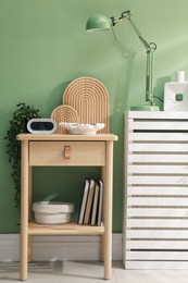 Photo of Wooden side table with stylish decor near green wall indoors