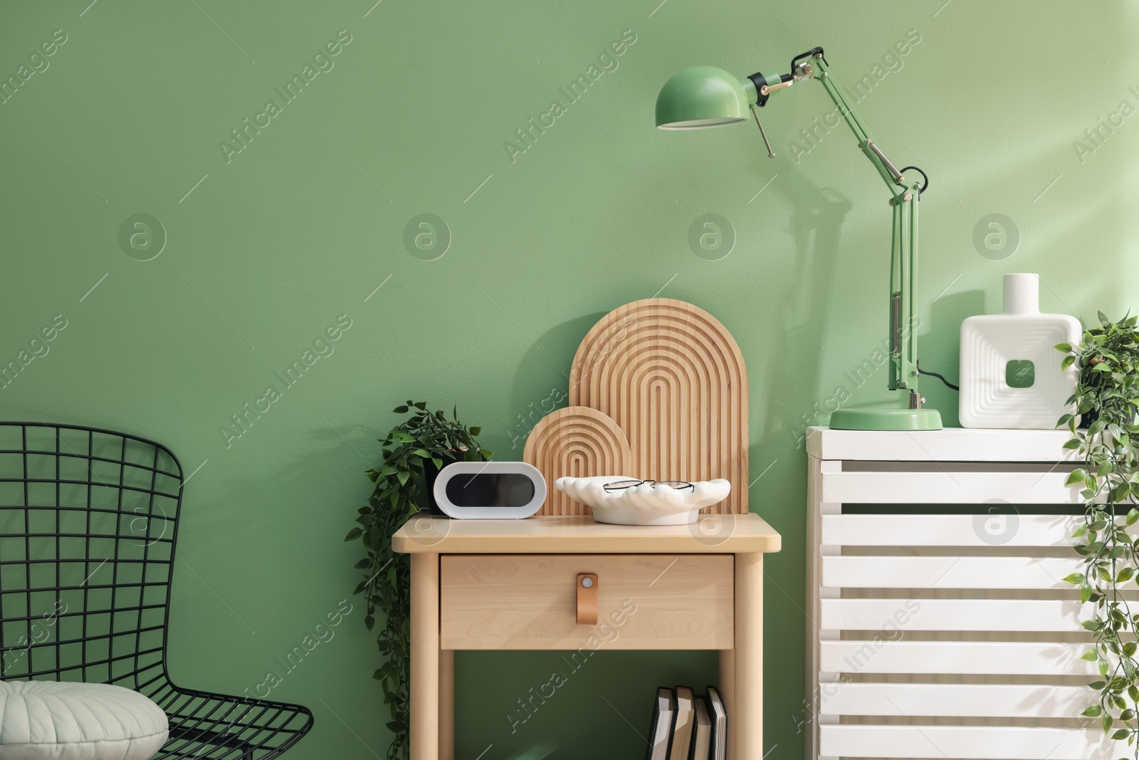 Wooden side table with stylish decor near green wall indoors Photo of Wooden side table with stylish decor near green wall indoors