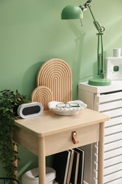 Photo of Wooden side table with stylish decor near green wall indoors