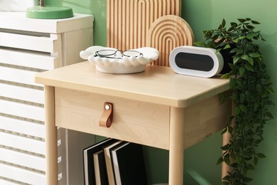 Photo of Wooden side table with stylish decor near green wall indoors, closeup