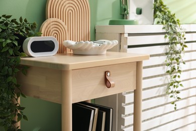 Photo of Wooden side table with stylish decor near green wall indoors, closeup
