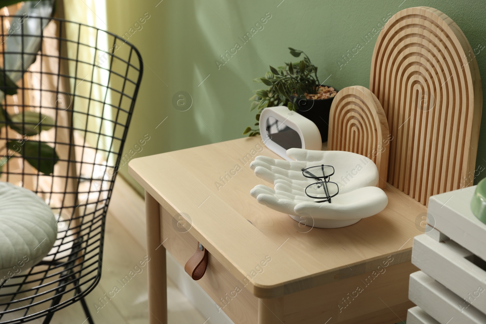 Wooden side table with stylish decor near green wall indoors, closeup Photo of Wooden side table with stylish decor near green wall indoors, closeup