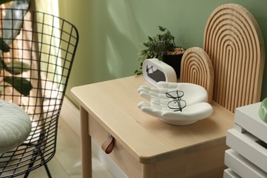 Photo of Wooden side table with stylish decor near green wall indoors, closeup