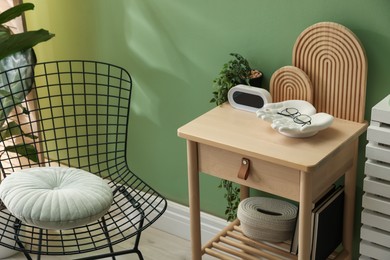 Photo of Wooden side table with stylish decor near green wall indoors
