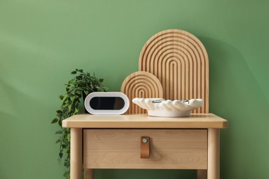 Photo of Wooden side table with stylish decor near green wall indoors, closeup