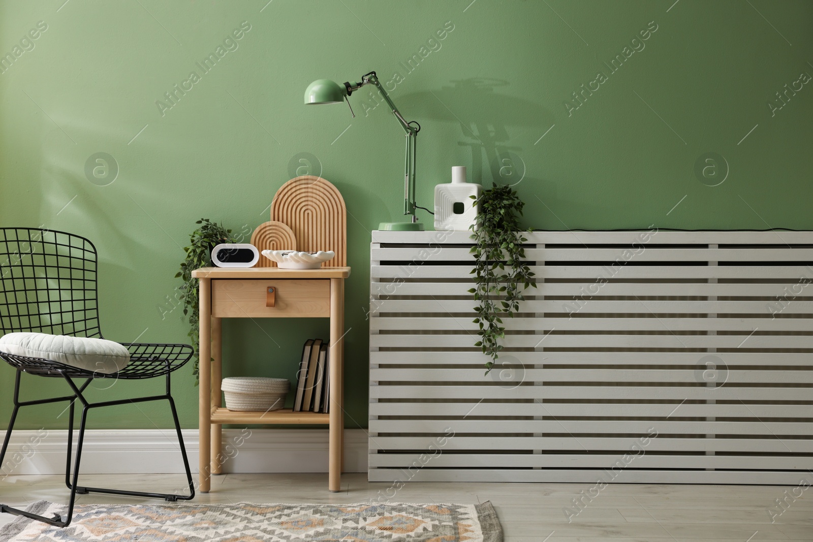 Wooden side table with stylish decor near green wall indoors Photo of Wooden side table with stylish decor near green wall indoors