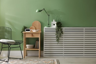 Photo of Wooden side table with stylish decor near green wall indoors