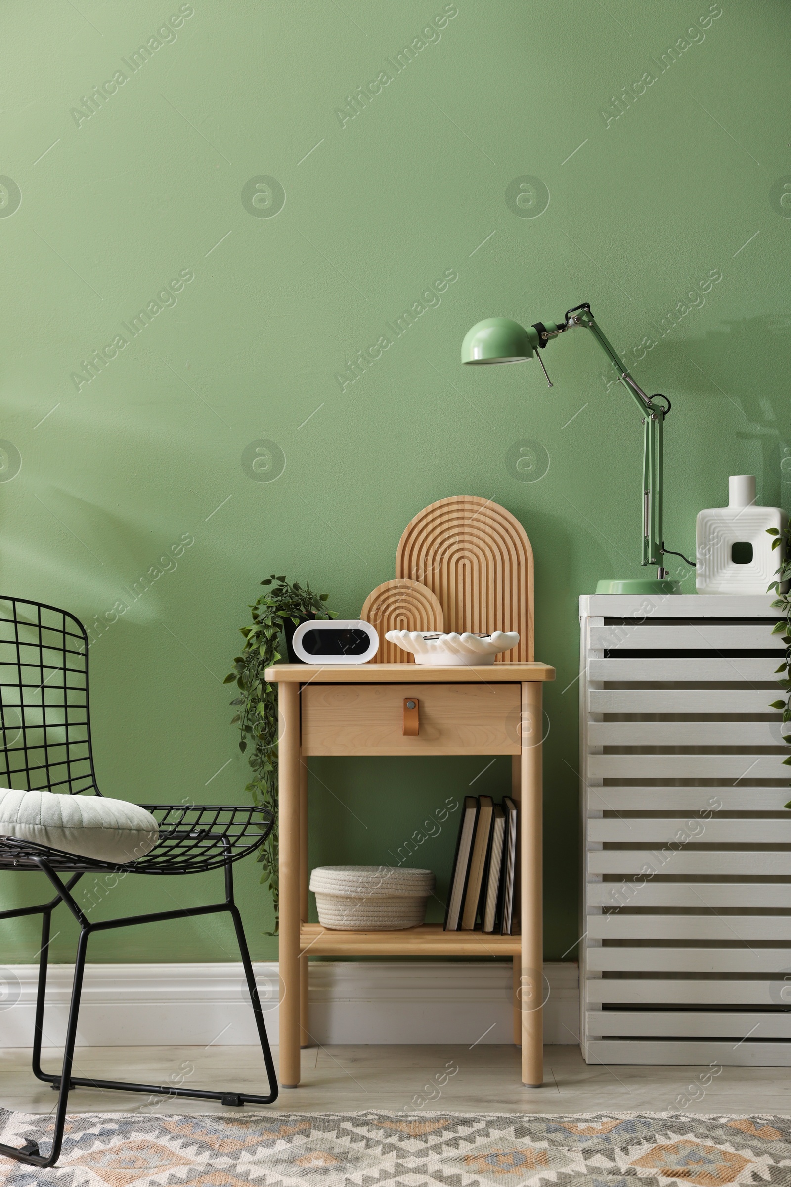 Wooden side table with stylish decor near green wall indoors Photo of Wooden side table with stylish decor near green wall indoors