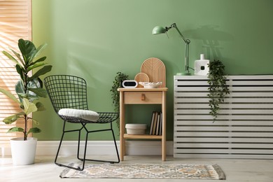 Photo of Wooden side table with stylish decor near green wall indoors