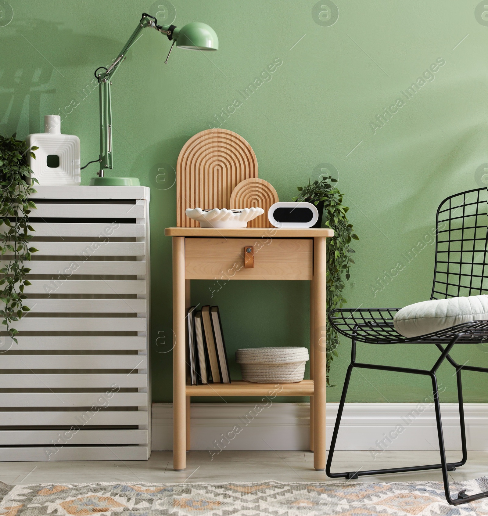 Wooden side table with stylish decor near green wall indoors Photo of Wooden side table with stylish decor near green wall indoors