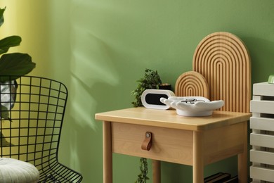 Photo of Wooden side table with stylish decor near green wall indoors, closeup