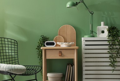 Photo of Wooden side table with stylish decor near green wall indoors