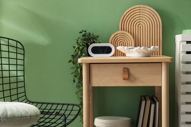 Photo of Wooden side table with stylish decor near green wall indoors, closeup