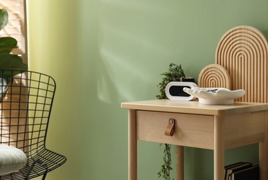 Photo of Wooden side table with stylish decor near green wall indoors, closeup. Space for text
