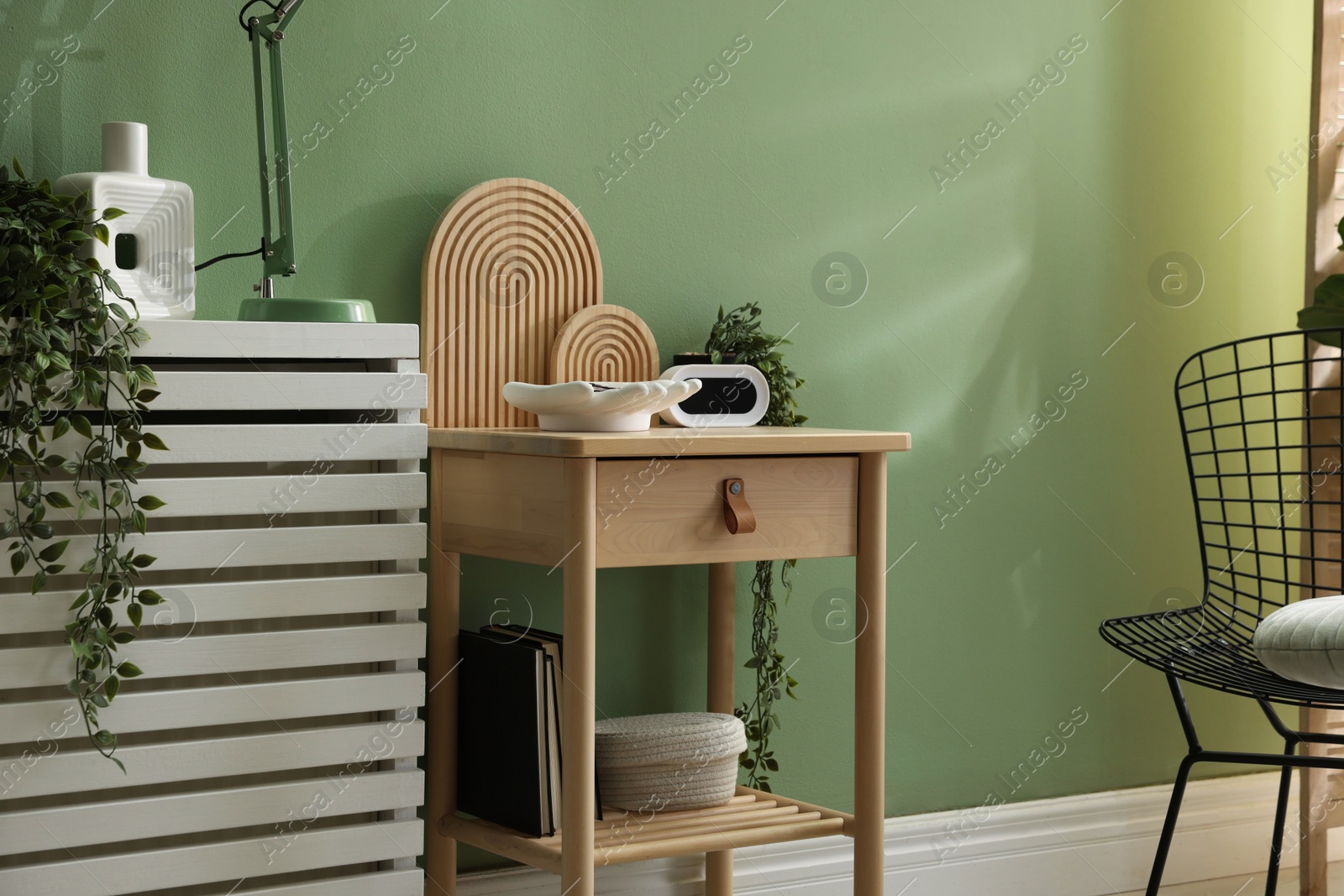 Wooden side table with stylish decor near green wall indoors Photo of Wooden side table with stylish decor near green wall indoors