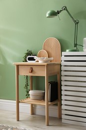 Photo of Wooden side table with stylish decor near green wall indoors